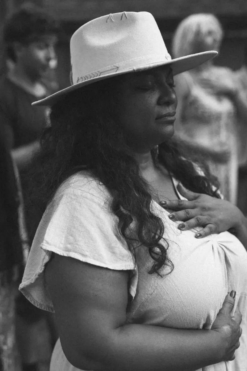 A woman in a quiet, contemplative moment, hand resting on her chest